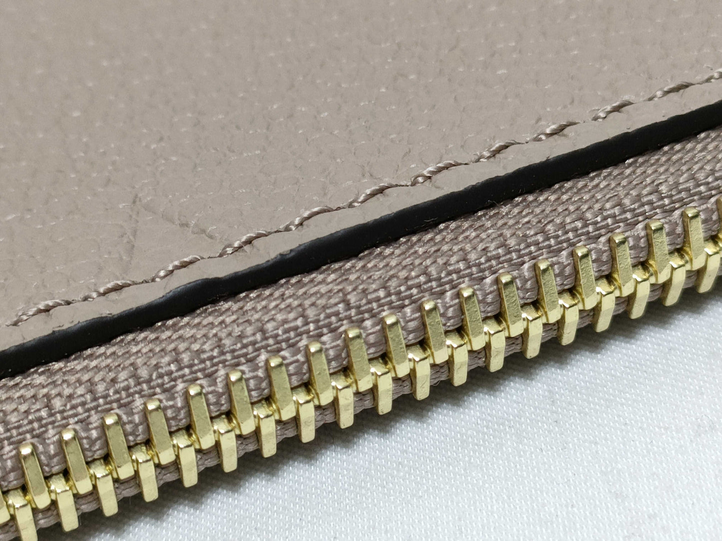 LOUIS VUITTON RFID verification impossible. Serial number verification impossible. Monogram Empreinte Louis Vuitton Neverfull Pouch in Taupe with Gold Hardware.
