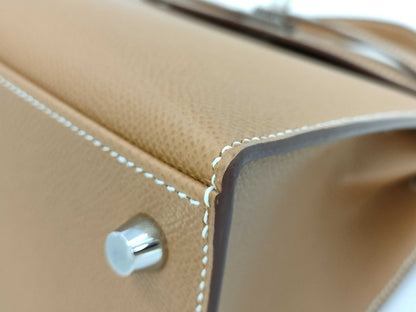 HERMES Kelly 25 handbag with gold exterior, Epsom finish, and silver hardware.