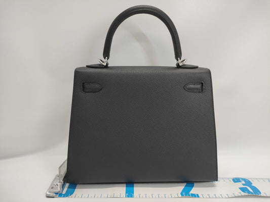 Brand new Hermès Kelly 25 shoulder bag in black with Epsom leather, electrum hardware, exterior stitching, K stamp, and protective seal.
