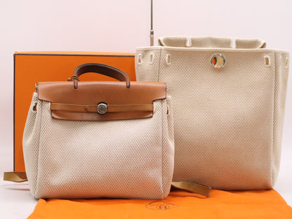 HERMES Toile GM x Leather Air Bag Ad PM Backpack in Brown, Beige, and Natural. Includes a padlock, two keys, a dust bag, and a box. H stamped. 2004.