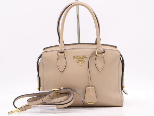 PRADA 2-way leather handbag in beige with GD hardware, shoulder strap, and clochette.